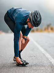Image showing Cycling, man and shoes preparation on road for outdoor sports adventure, triathlon or workout. Fitness, training and athlete cyclist man on street with helmet getting ready for cycle exercise.