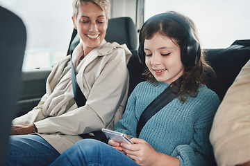 Image showing Travel, driving and child with grandmother in car on a smartphone and headphones for transportation or safety belt happiness. Insurance and old woman with kid games using phone mobile app on journey