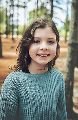 Image showing Nature, happiness and portrait of child in forest with smile on face enjoy hiking trail in woods. Freedom, adventure and trees, happy young girl smiling on holiday hike or fun walking in outdoor park