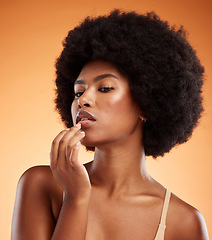 Image showing Model woman with lip balm makeup in studio, portrait with skincare product advertising or natural cosmetic on face. Lip gloss on mouth, beauty on orange background or moisturizer cream lipstick