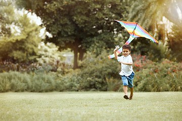 Image showing Child, kite and grass while running for wind to lift, air and sky while play, fun and happy outdoor. Boy, toys and lawn in garden, backyard or park in sunshine, summer and nature while playing