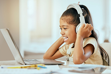 Image showing Girl, laptop and headphones with smile, music or video on desk in homeschool, learning and education, Child, computer and happy for podcast on internet, web or app by table in house for online class