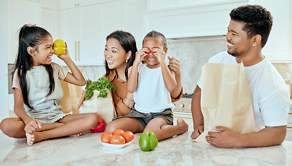 Image showing Asian, vegetables and family in kitchen for playing at table, happy or together for bonding. Mom, dad and children with smile at counter for health, food or nutrition with bags after shopping in home