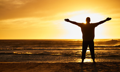 Image showing Silhouette of man with view, sunset and beach with arms out by the ocean, carefree and peace, freedom on vacation outdoor. Free, sunshine and hands up, travel and adventure in nature, sea water.