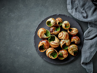 Image showing plate of baked escargot snails filled with parsley and garlic bu