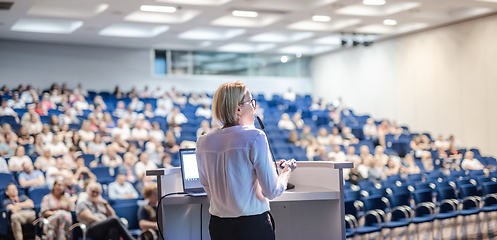 Image showing Female speaker giving a talk on corporate business conference. Unrecognizable people in audience at conference hall. Business and Entrepreneurship event.