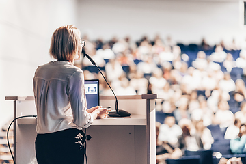 Image showing Female speaker giving a talk on corporate business conference. Unrecognizable people in audience at conference hall. Business and Entrepreneurship event.