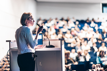 Image showing Female speaker giving a talk on corporate business conference. Unrecognizable people in audience at conference hall. Business and Entrepreneurship event.