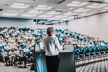 Image showing Female speaker giving a talk on corporate business conference. Unrecognizable people in audience at conference hall. Business and Entrepreneurship event.