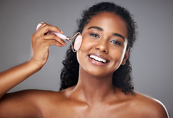 Image showing Skincare, portrait and woman with a face roller for wellness, beauty and skin routine in studio. Happy, smile and girl model from Brazil with rose quartz cosmetic tool for self care facial treatment.