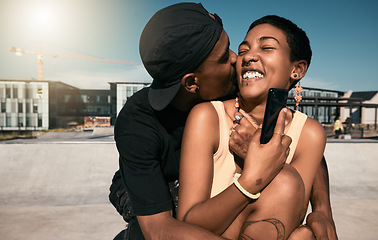 Image showing Couple, hug and kiss while bonding in city with phone for social media and internet search for fun Brazilian activity. Smile, happy and love man and black woman with 5g mobile technology and fashion