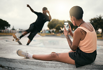 Image showing Man on skateboard in park, woman photograph skater boyfriend in city on smartphone or urban lifestyle in Los Angeles. Street fashion, young edgy black couple streaming video online or social media