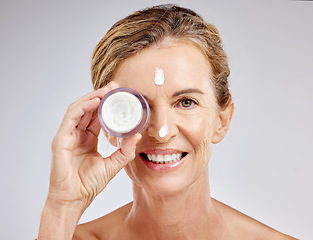 Image showing Skincare, beauty and cream on face of mature woman with a smile for luxury spa self care on gray studio background. Senior, cosmetic wellness and nature cosmetic health with collagen lotion treatment