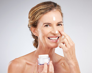 Image showing Skincare, elderly and woman with facial cream or face cream product for healthy glowing face in studio portrait. Smile, mockup and happy mature beauty model grooming with sunscreen natural cosmetics