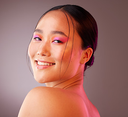 Image showing Beauty, makeup and face of model in studio with neon, creative and color vaporwave, eyeshadow and mockup. Portrait, art and Chinese model smile, happy and relax with facial cosmetics grey background