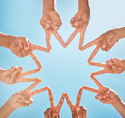 Image showing Teamwork, community and group support with fingers in a star shape from below against a blue sky background. A diverse crowd of people with hands joined together for motivation, unity and peace