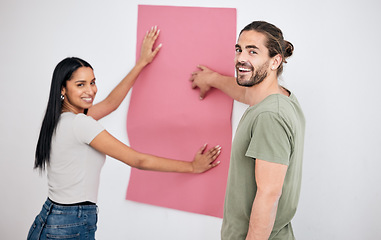 Image showing Couple, wallpaper and home, design or renovation with pink poster. Smile, diversity and happy man and woman with banner or paper sheet for decoration, remodeling or renovating in house together