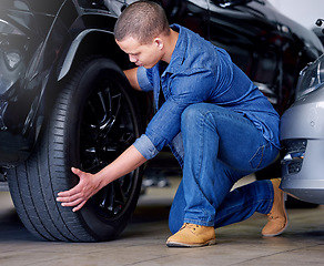 Image showing Man, car mechanic and tire change in garage, vehicle maintenance or service. Expert, professional and repairman in automobile workshop or auto shop working on wheel, tyre repair or safety inspection