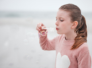 Image showing Girl, fun and blowing soap bubbles with fun, freedom and vacation at the beach. A young female playing and relaxing on her holiday outdoor at the sea in with a toy to play, entertain and free outside