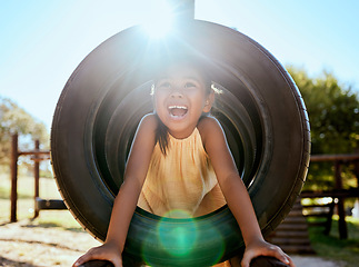 Image showing Child, smile and park on jungle gym, tyre and playing in sunshine, summer and outdoor while excited. Happy, girl and wow for laugh, happiness and playground in lens flare, comic and nature in Orlando