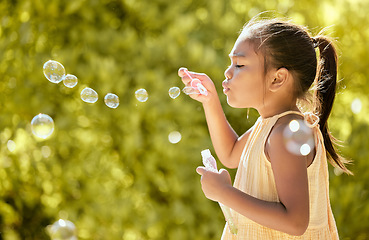 Image showing Bubbles, outdoor and girl in a nature park feeling relax, playful and content by sunshine. Child from Taiwan blow a bubble in the spring sun feeling peace, calm and content with happiness on vacation