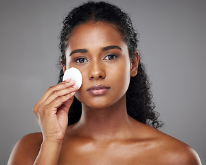 Image showing Beauty, face and cotton pad with a model black woman exfoliating her skin in studio on a gray background. Cosmetics, treatment and skincare with an attractive young female using a natural product