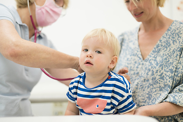 Image showing Infant baby boy child being examined by his pediatrician doctor during a standard medical checkup in presence and comfort of his mother. National public health and childs care care koncept.