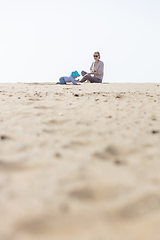 Image showing Mother playing his infant baby boy son on sandy beach enjoying summer vacationson on Lanzarote island, Spain. Family travel and vacations concept.