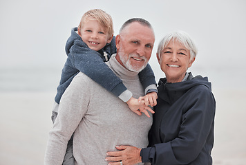 Image showing Family, portrait and child with grandparents at a beach, hug, relax and smile while having fun on vacation. Travel, happy family and senior couple enjoy ocean trip and quality time with grandchild