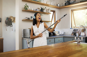 Image showing Cleaning, headphones and black woman singing and playing air guitar music with a broom in a house. Fun, playful and happy female enjoying a clean home, kitchen or room while streaming song or radio