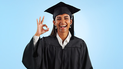 Image showing Graduate woman, ok sign and smile in studio with review with vote, choice and support by blue background. Graduation, girl and portrait with icon, emoji or decision with celebration, goals or success