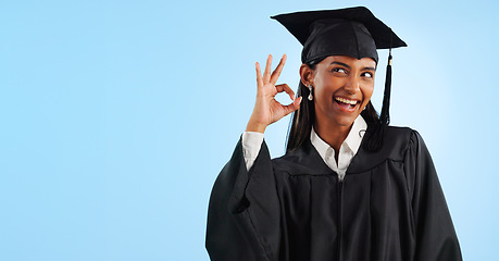 Image showing Woman, graduation and space with ok sign, studio and review for vote, choice or support by blue background. Student girl, thinking and celebration for icon, emoji and decision for mockup with goals