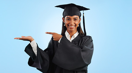 Image showing Graduation, portrait and happy woman point, palm gesture and advertising learning, university info or college study. Studio mockup space, student commercial ads or school graduate on blue background