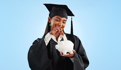 Image showing Woman, graduation and piggy bank in studio, saving and cash for investing, future or goals by blue background. Student girl, banking and money with thinking, decision and choice for financial plan