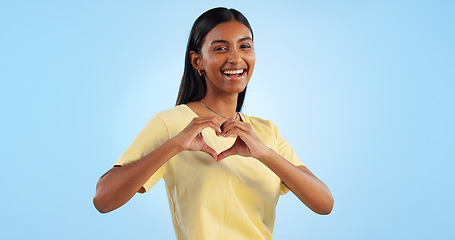 Image showing Heart, hands and woman in portrait with support, charity and love sign with smile on blue background. Health, wellness and donation with care, icon or symbol, emoji and happy with kindness in studio