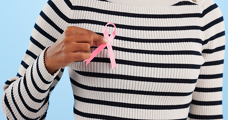 Image showing Hand, pink ribbon and breast cancer support with awareness and healthcare icon on blue background. Person in studio, medical symbol and wellness with care, trust and kindness, solidarity and campaign