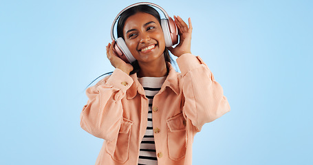 Image showing Happiness, woman and headphones, listening to music in studio and entertainment on blue background. Mockup space, audio streaming and fun with dancing, energy and freedom with wireless tech and sound