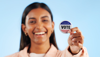 Image showing Woman, hand and pin for vote by showing in studio for mock up in politics on blue background. Indian person, smile and excited for government election or campaign with support in community engagement