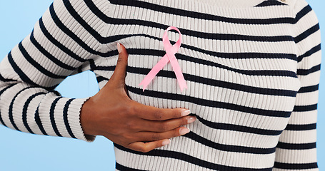 Image showing Hand, show pink ribbon and breast cancer support with awareness and health icon on blue background. Person in studio, medical symbol and wellness with care, trust and kindness in solidarity campaign