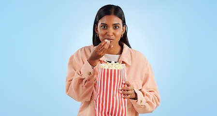 Image showing Portrait, watching tv and woman with popcorn, excited and happiness on a blue studio background. African person, girl or model with cinema snack, eating a treat or streaming a movie with mockup space