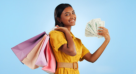 Image showing Woman, shopping bag and cash fan, wealth and commerce with customer in portrait on blue background. Money, financial freedom and retail, fashion and product choice, rich and store discount in studio