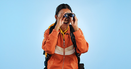 Image showing Hiking studio, binocular and woman watch trekking, backpacking and travel adventure view, sightseeing or bird watching. Wow, journey and happy camper vacation, freedom or discovery on blue background