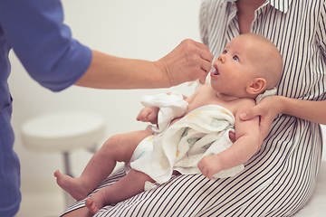 Image showing Pediatrician administring oral vaccination against rotavirus infection to little baby in presence of his mother. Children health care and disease prevention