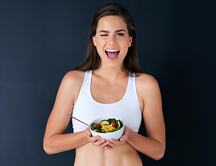 Image showing Happy woman, portrait and wink with salad for diet, lose weight or natural nutrition against a studio background. Female person or model with bowl of vegetables for food or healthy meal on mockup