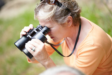 Image showing Senior, woman and binocular in forest for travel, sightseeing or vacation and scenery in nature. Elderly, lady or person in woods for holiday, adventure or experience with hiking, explore or activity