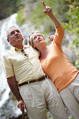 Image showing Senior, man and woman with pointing in forest for travel, sightseeing or holiday with waterfall. Elderly, couple or face and showing view for vacation and adventure on retirement or tourism in nature