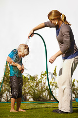 Image showing Boy, woman and hose pipe with water fun, splash and playing outdoor in backyard or garden for sunshine. Kid, people or mother on grass or lawn with happiness, activity and enjoyment in summer weather