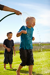 Image showing Kids, boys and hose pipe with water fun, splash and playing outdoor in backyard or garden for sunshine. Children, brother and people on grass or lawn with happiness, activity and enjoyment in summer