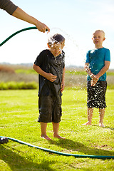 Image showing Children, boys and hose pipe with splash, water fun and playing outdoor in backyard or garden for sunshine. Kids, brother and people on grass or lawn with happiness, activity and enjoyment in summer