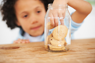 Image showing Cute, cookie jar and boy child by the kitchen counter eating a sweet snack or treat at home. Smile, dessert and hungry young kid enjoying biscuits by a wooden table in a modern family house.